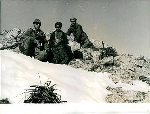 תצלום וינטג 'של שני חיילים וילד צעיר יושב על הר מושלג ורוקי.